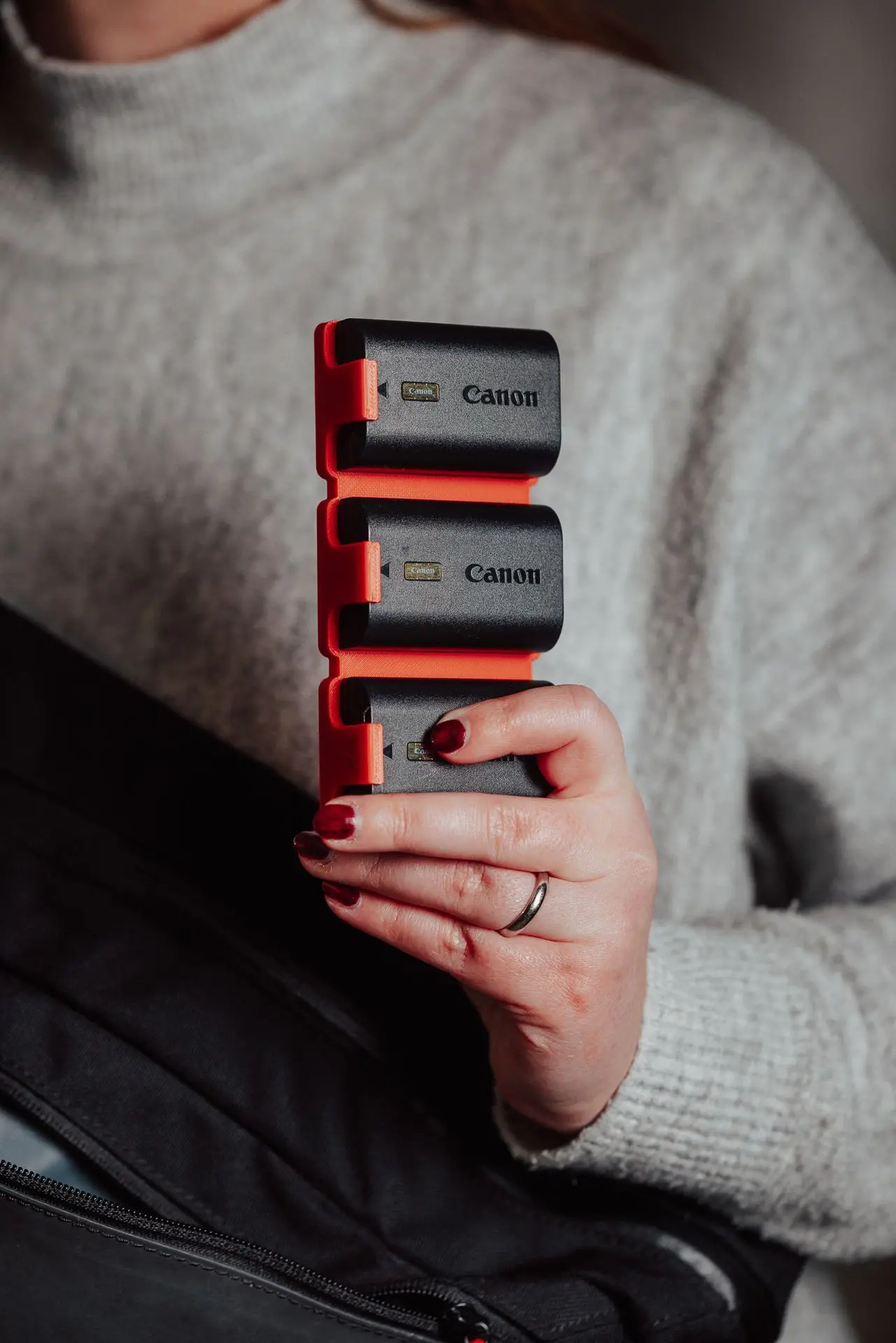 A girl showing a 3d printed Hōld Trio holding three batteries