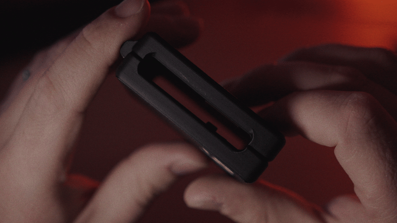 Kōlor in someone's hand, sideways. We can see the space between the two sides, making it attachable to a belt.